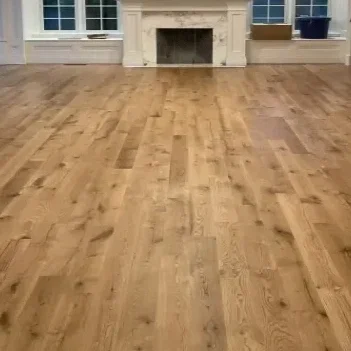 Empty room with hardwood floor and a fireplace, with large windows on each side.