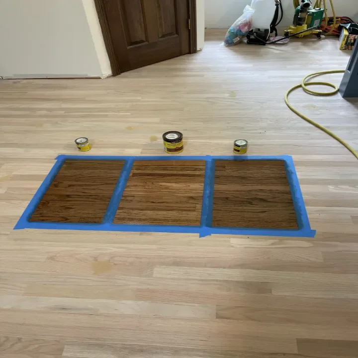 Wooden floor with three cans of wood stain or finish showing options to the owner.