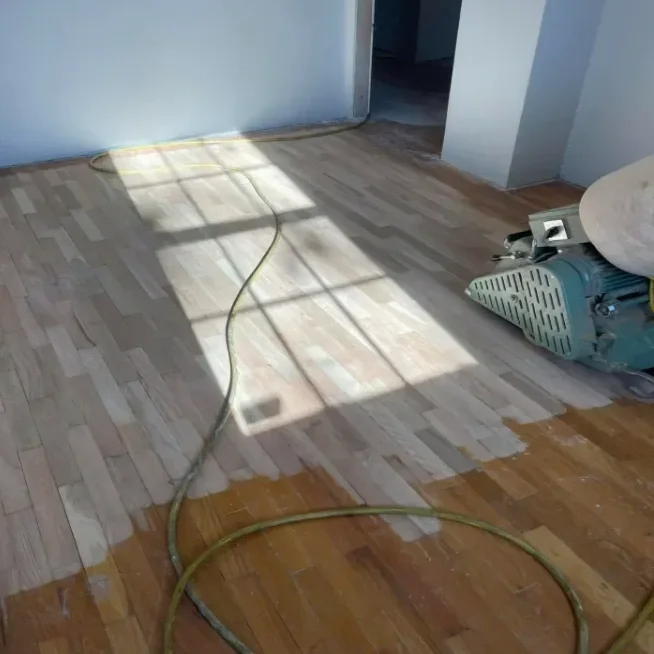 Hardwood flooring being sanded or refinished, with a floor sander.