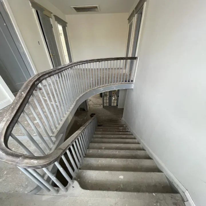Empty interior staircase with metal handrail leading downstairs.