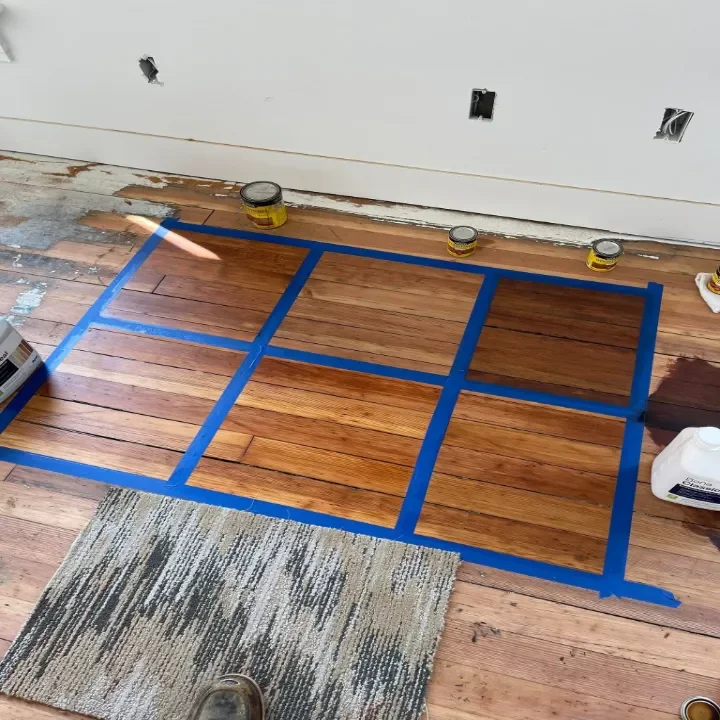 Flooring installation in progress with various stain options being provided.