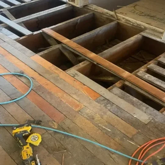Exposed wooden floor joists being repaired.