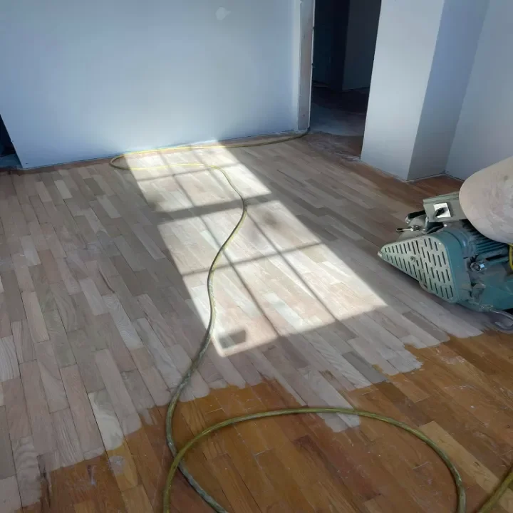 A room with a partially sanded wooden floor.