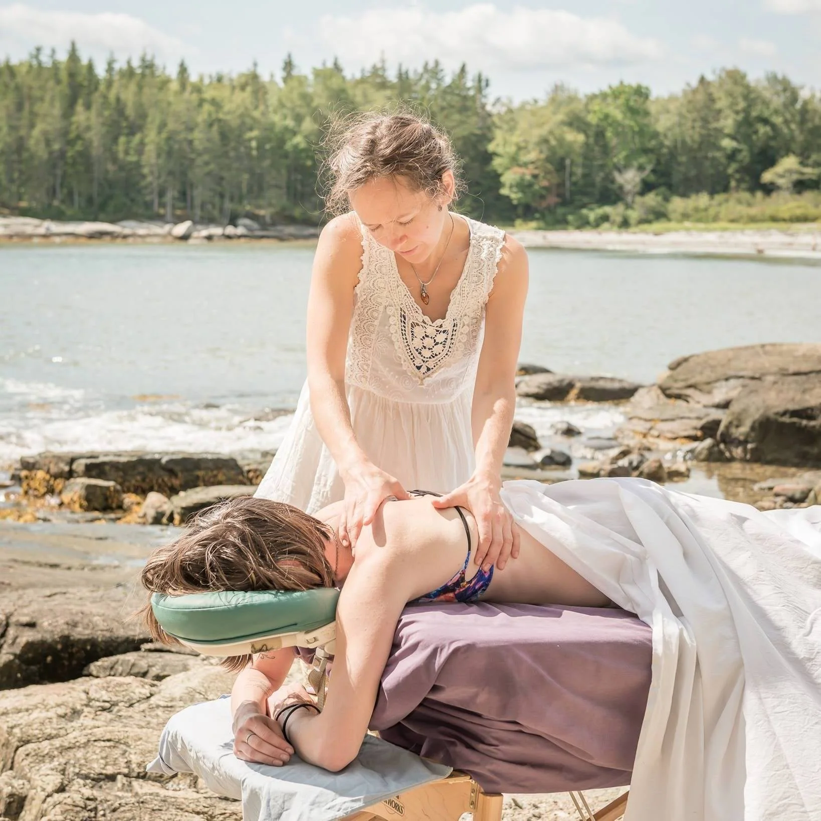A woman giving a massage outdoors at one of Maine beautiful and iconic beaches.
