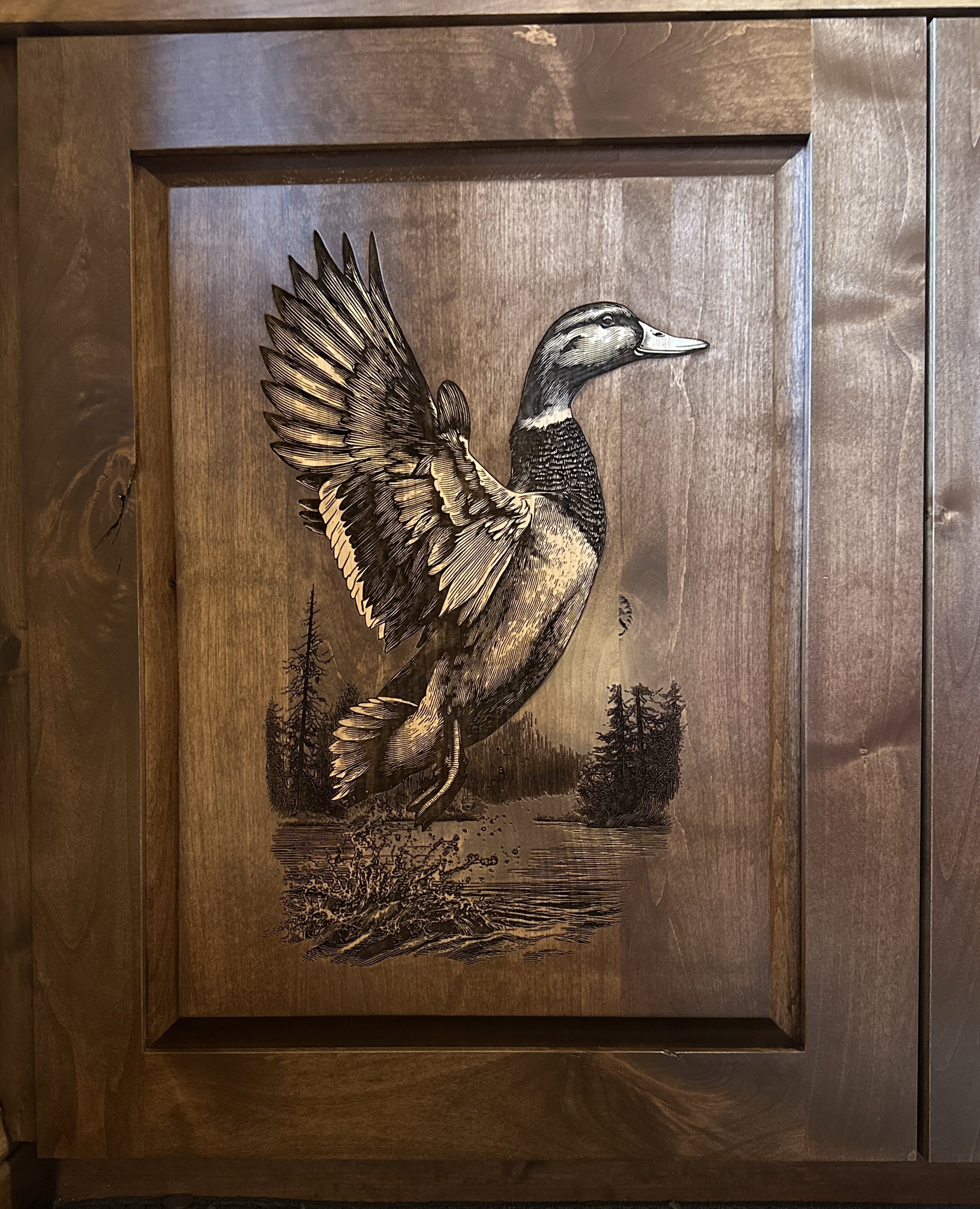 A wood-framed artwork of a duck with spread wings, standing in a natural setting with trees and a mountain in the background.