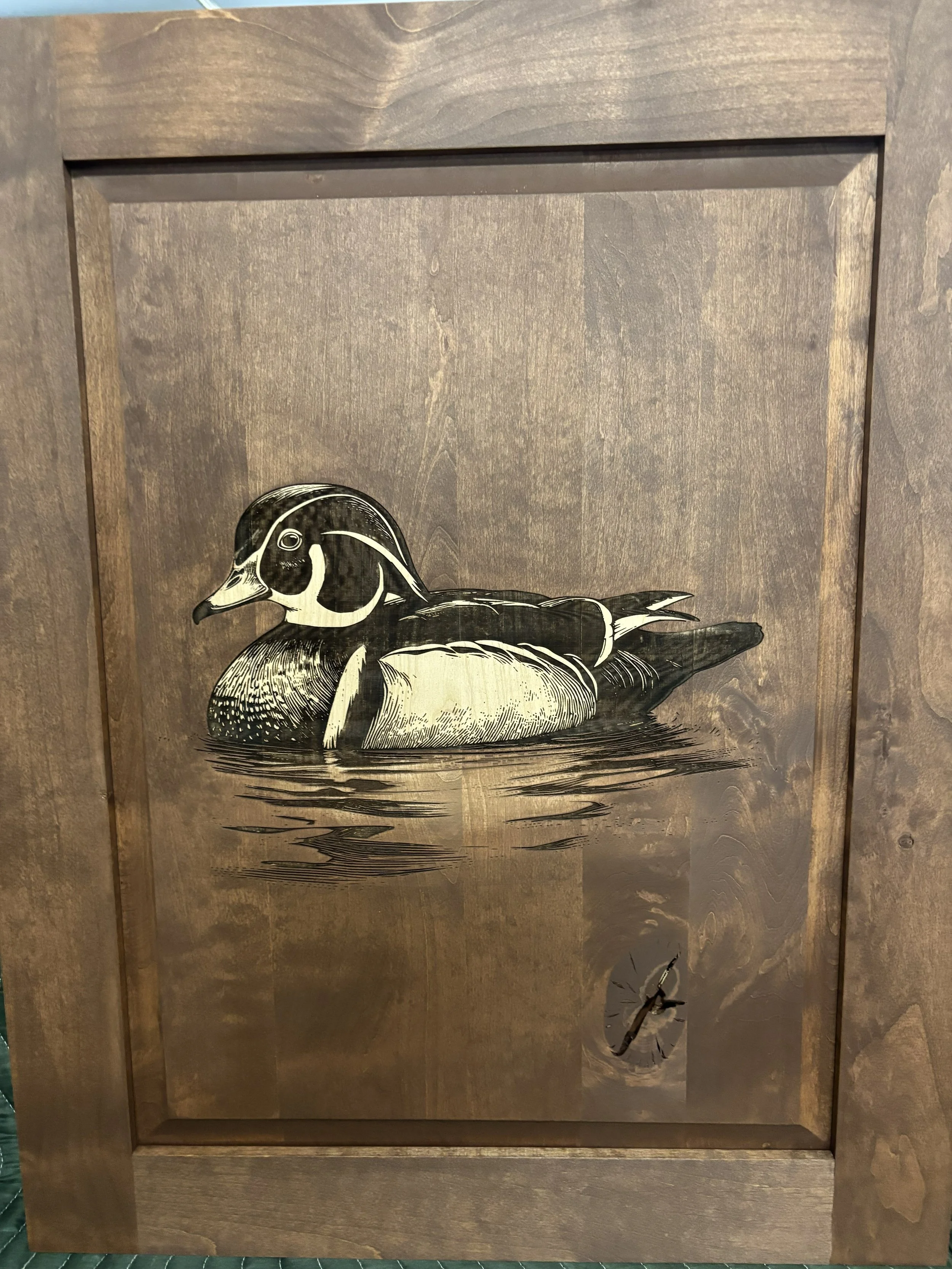 Decorative metal panel with a detailed black and white illustration of a mallard duck resting on water, attached to a wooden frame.