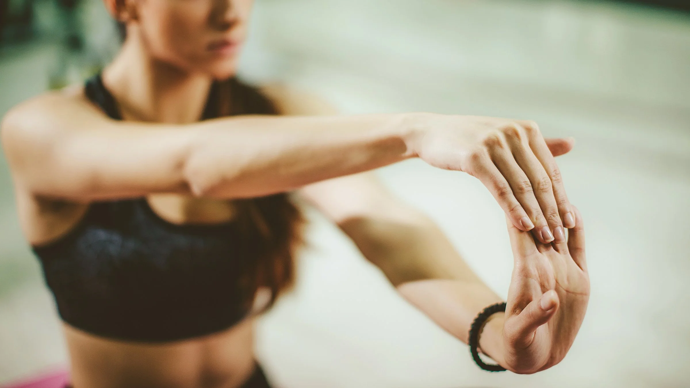 A woman extending her arm and hand in a stretching pose with focus on her hand and arm.