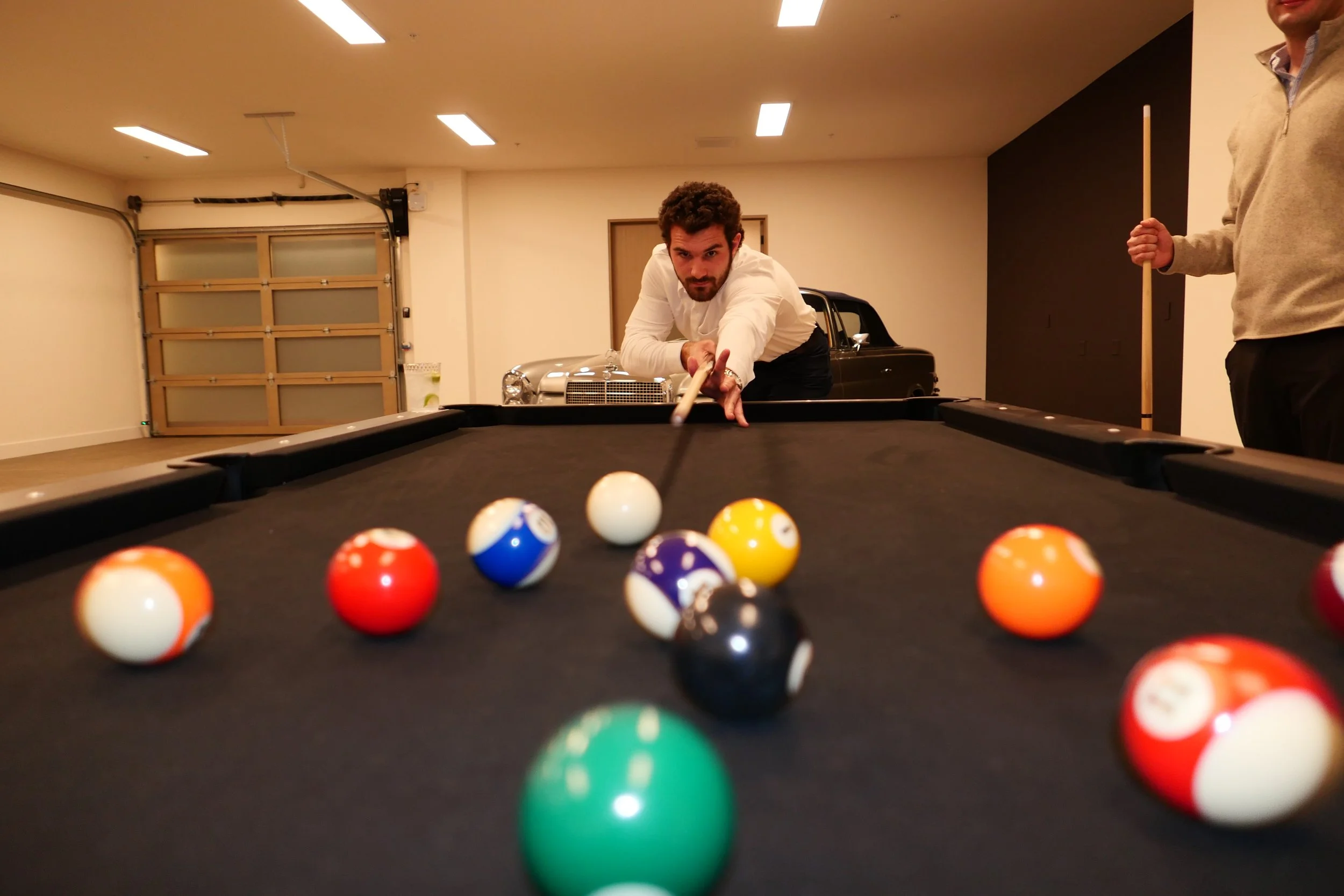 A man preparing to take a shot while playing pool, with billiard balls on the table in the foreground.