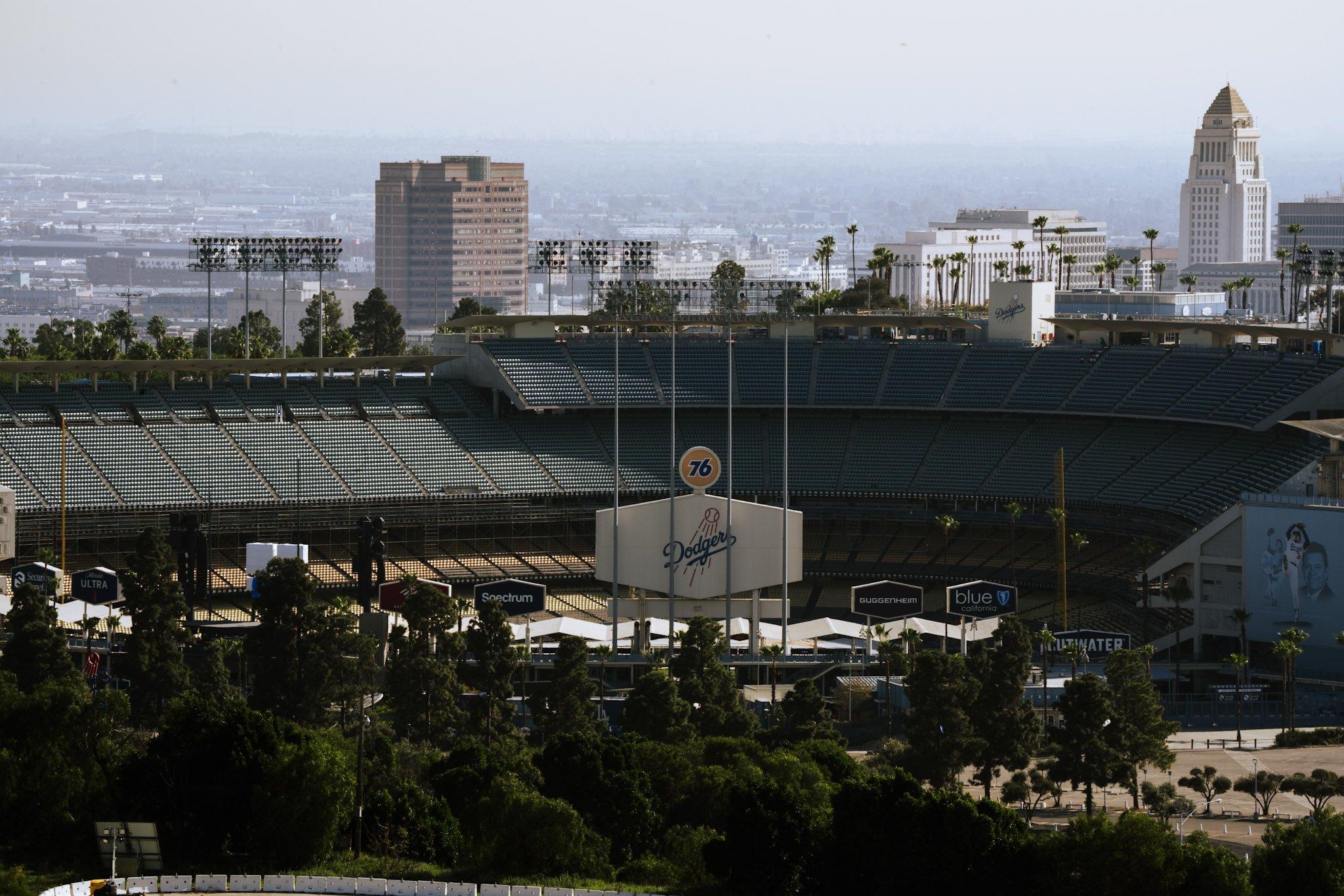 A view of a baseball stadium in Los Angeles with a distant cityscape including tall buildings, palm trees, and foggy skies.