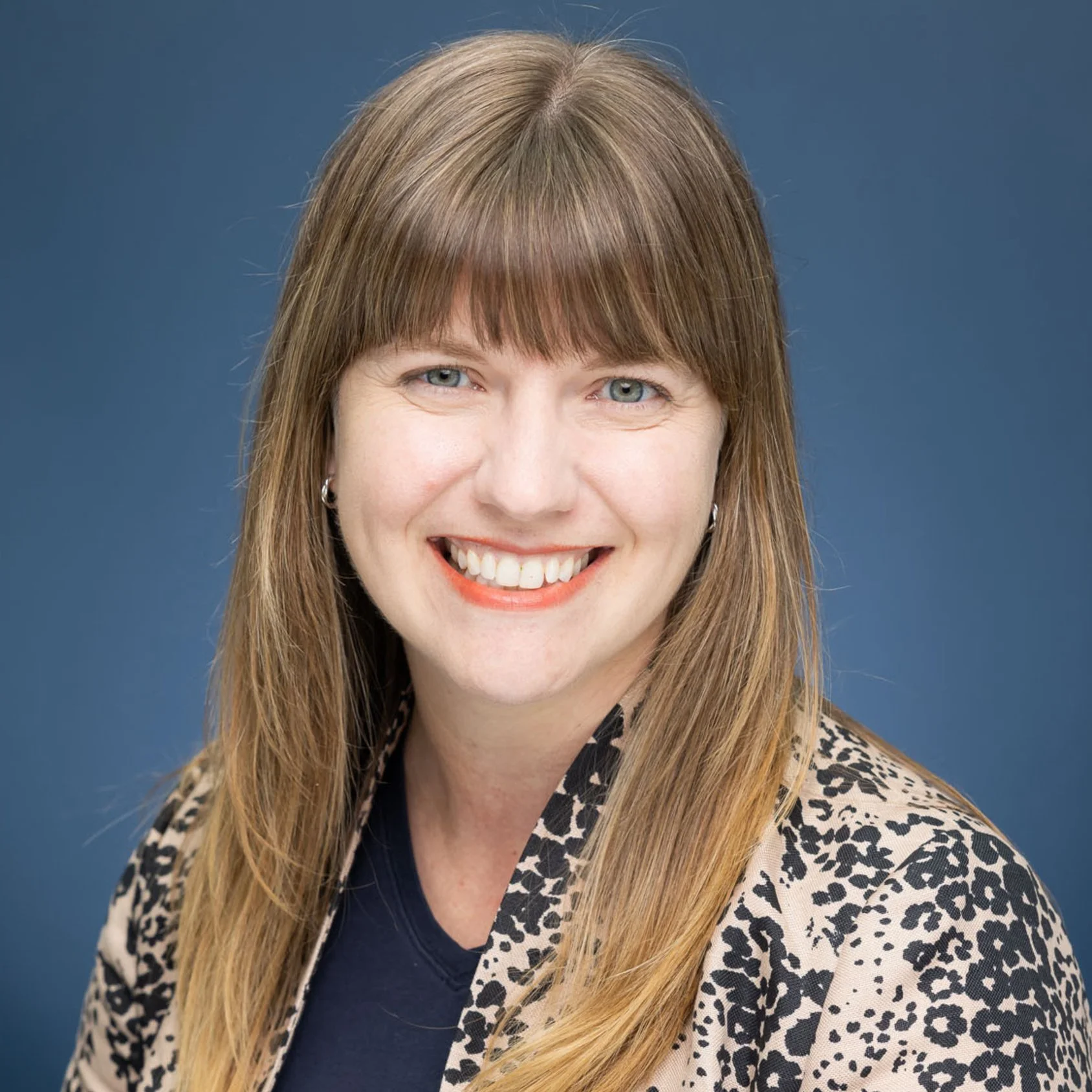 A woman wearing a blazer is smiling into the camera