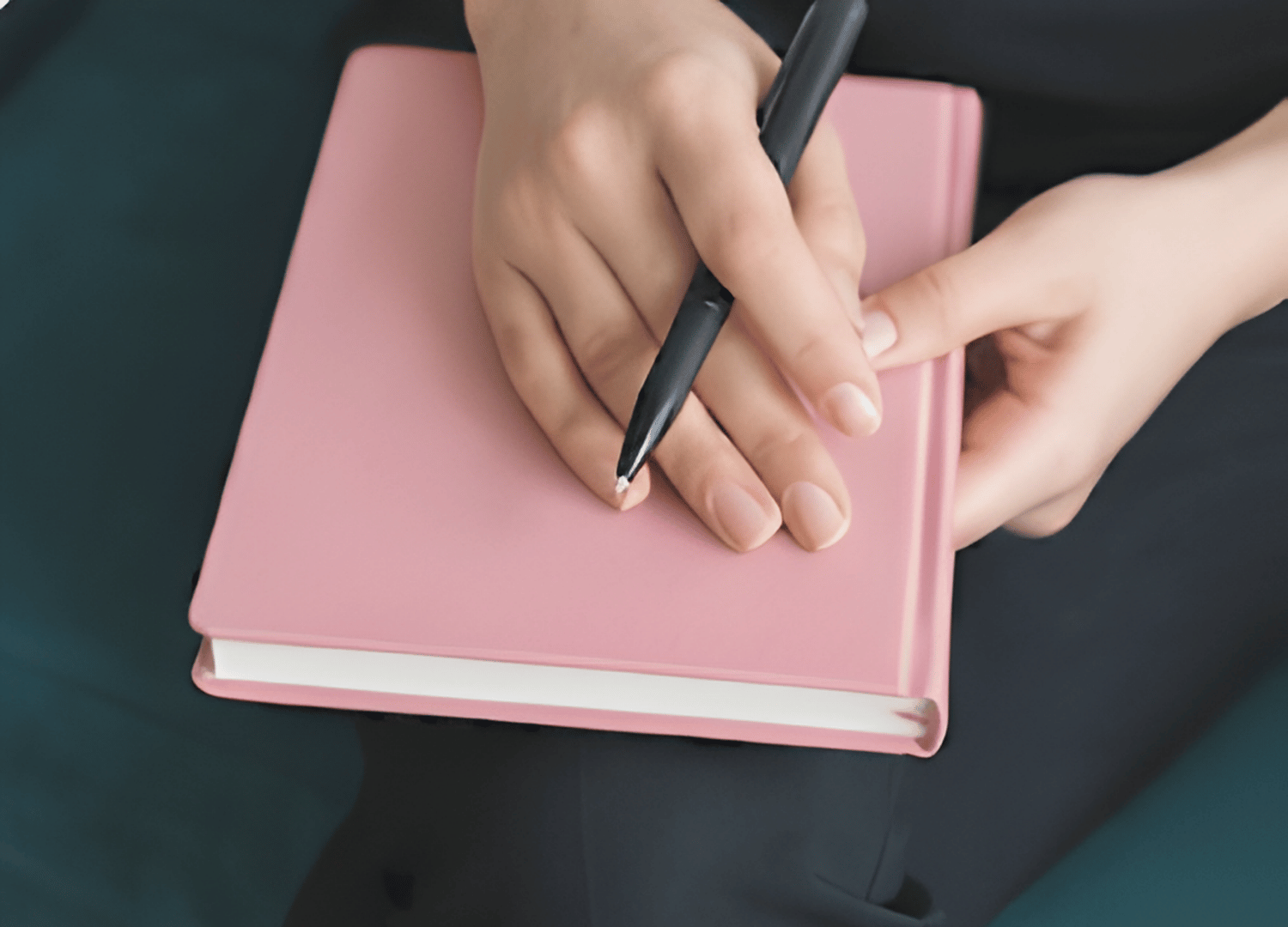 Hands holding a pink journal representing self-reflection and emotional growth in therapy at Throughline Psychotherapy in Raleigh, NC