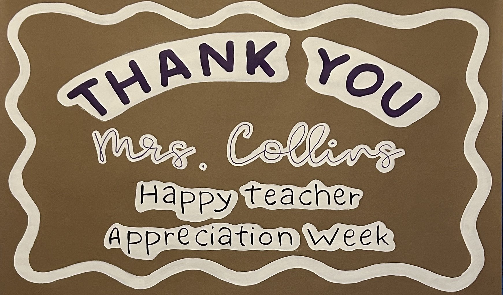 Brown bulletin board with white decorative border, displaying a message thanking Mrs. Collins for being a great teacher during Appreciation Week. The message includes "THANK YOU", "Mrs. Collins," "Happy teacher" and "Appreciation Week" in hand-written style.