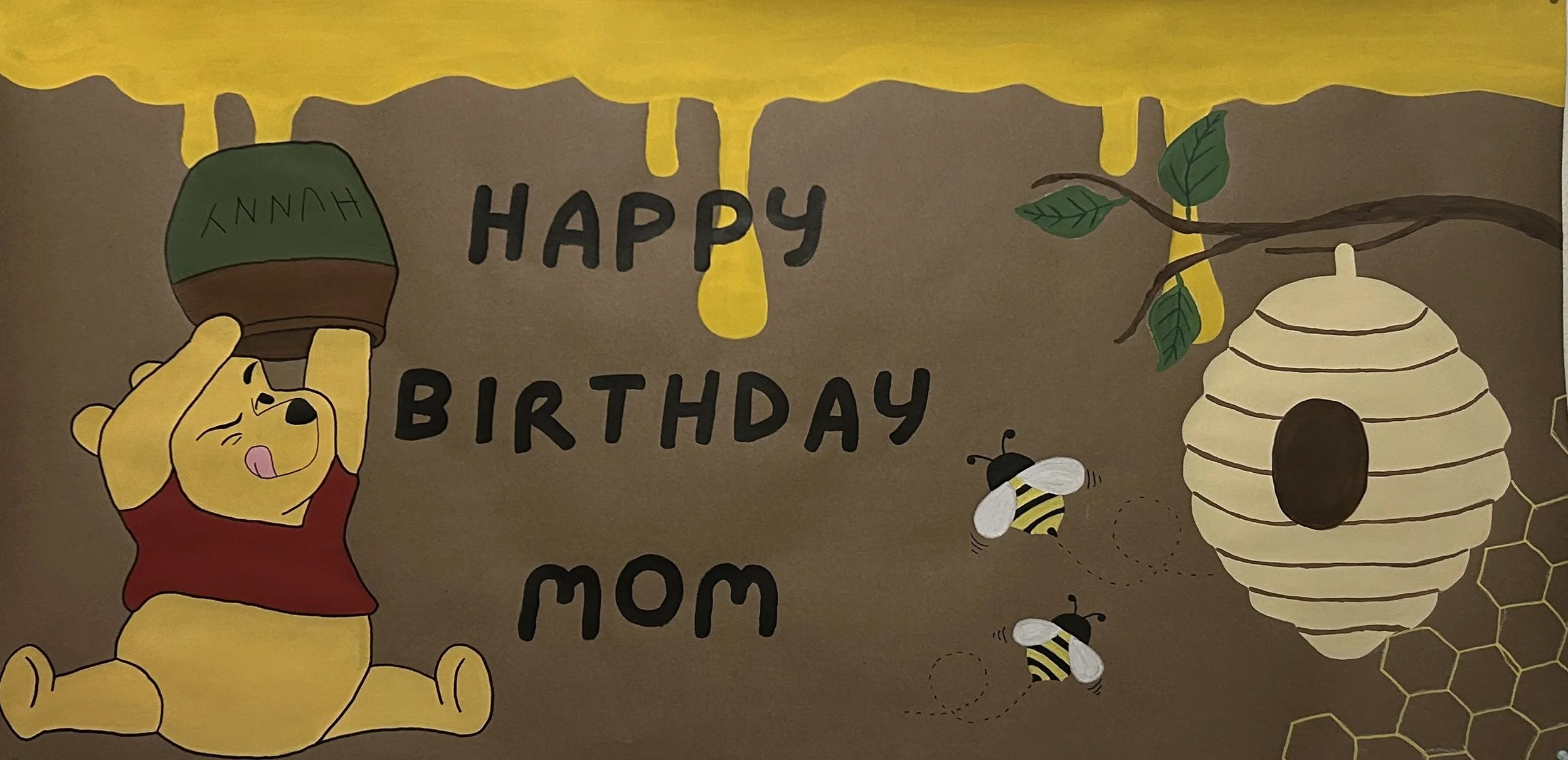 A colorful birthday poster featuring Winnie the Pooh holding a plant pot labeled 'Hunny,' with the message 'Happy Birthday Mom,' a honey bee, a beehive, and honeycomb patterns.