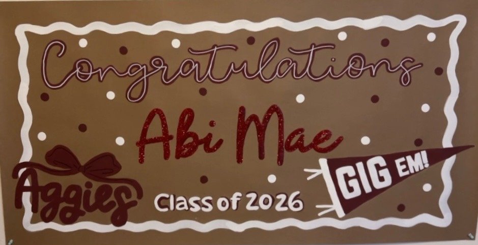 Decorative congratulatory sign for Abi Mae, a member of the class of 2026, with the word "GIG EM!" on a flag graphic.