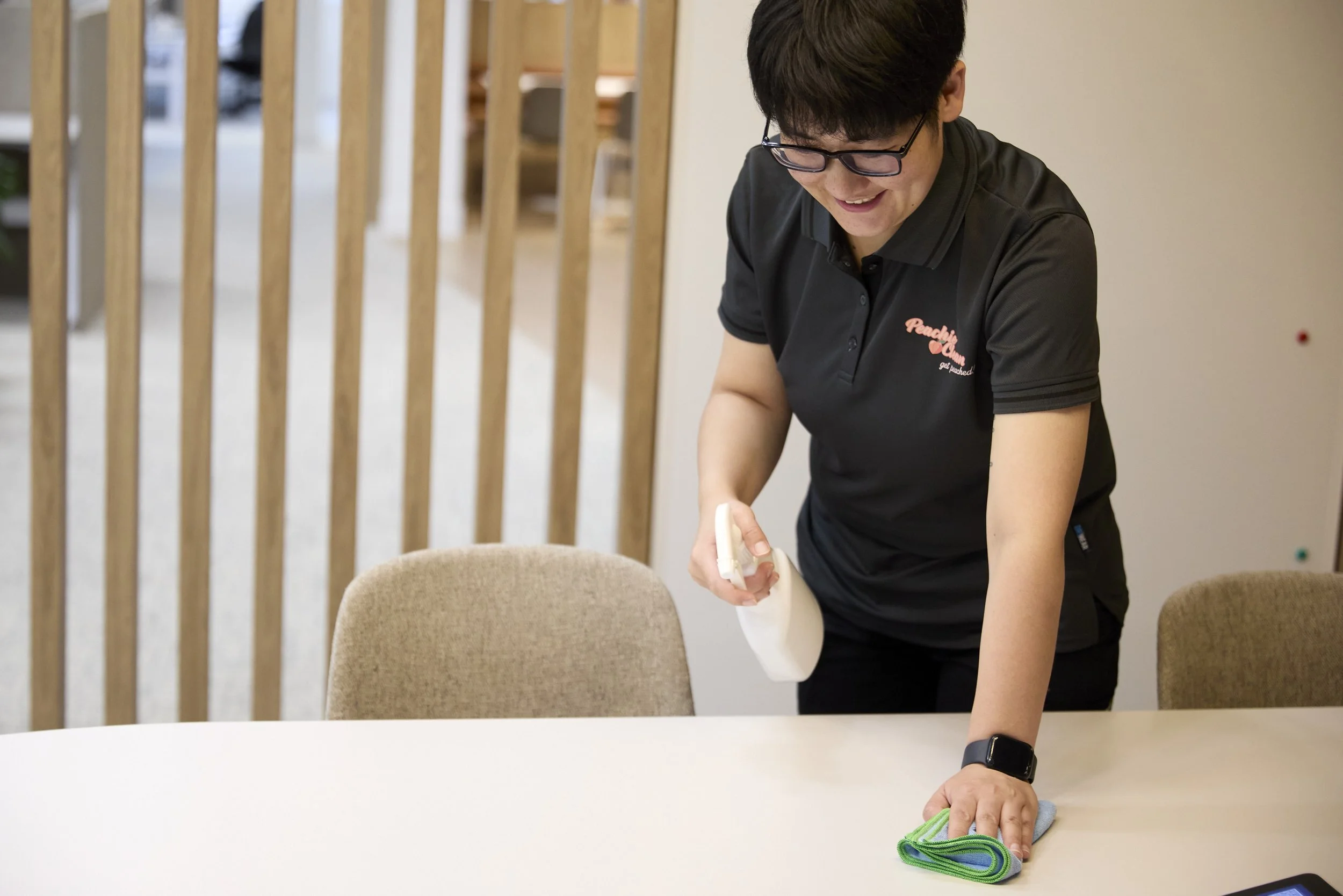 Peachie Clean team member cleaning meeting table in Hobart office, wiping and sanitising surfaces in a professional workspace