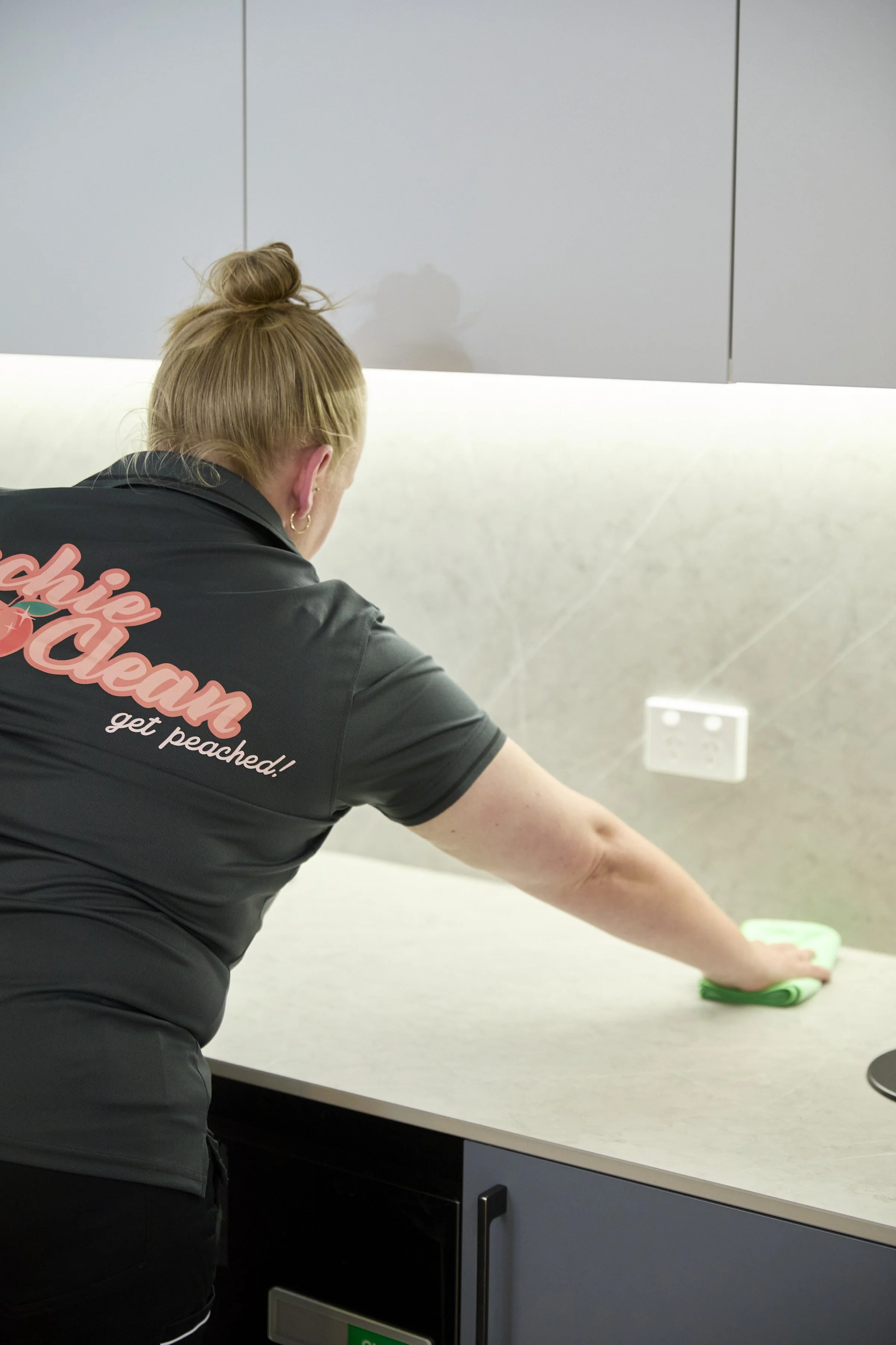Peachie Clean team member wiping kitchen surfaces in Hobart office, maintaining hygiene in a commercial workplace environment