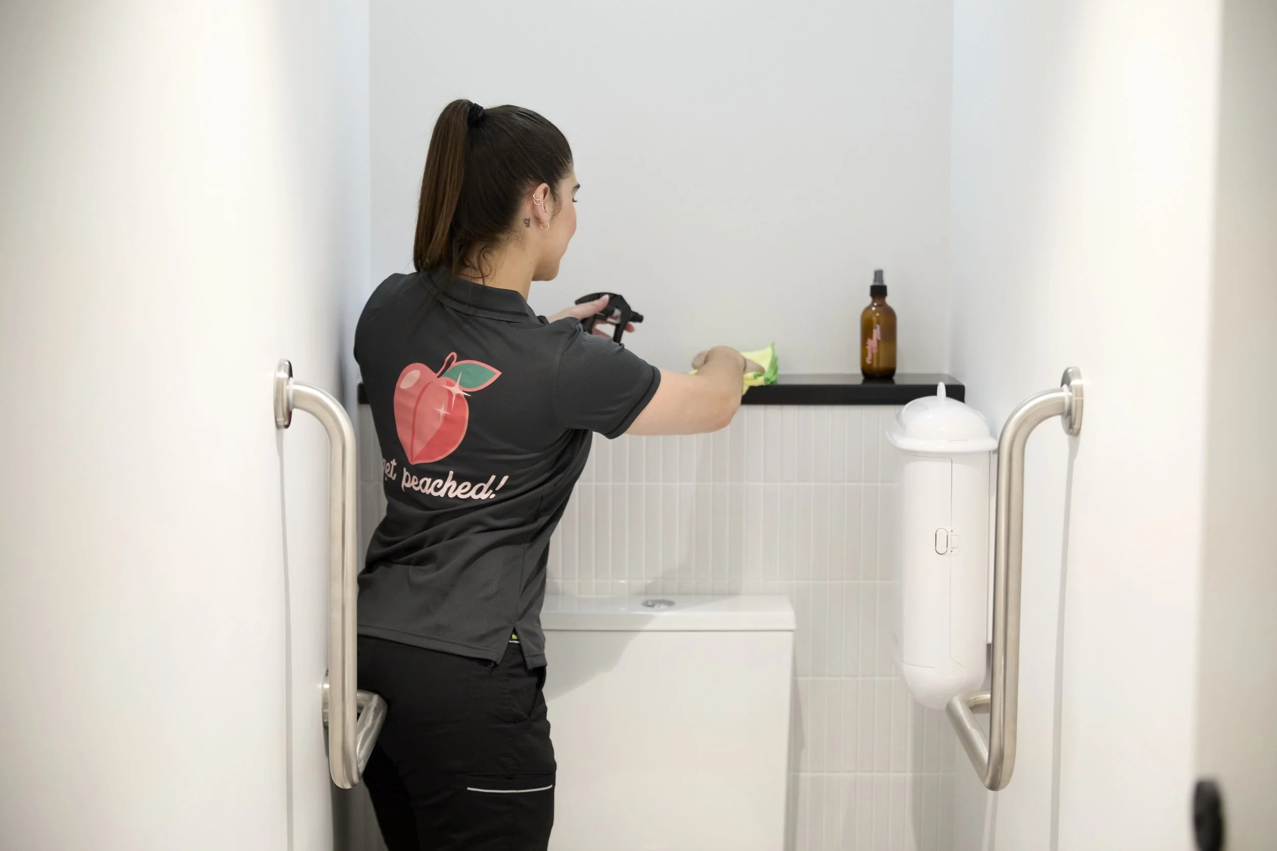 Peachie Clean team member sanitising restroom surfaces in Hobart workplace, delivering professional commercial cleaning services