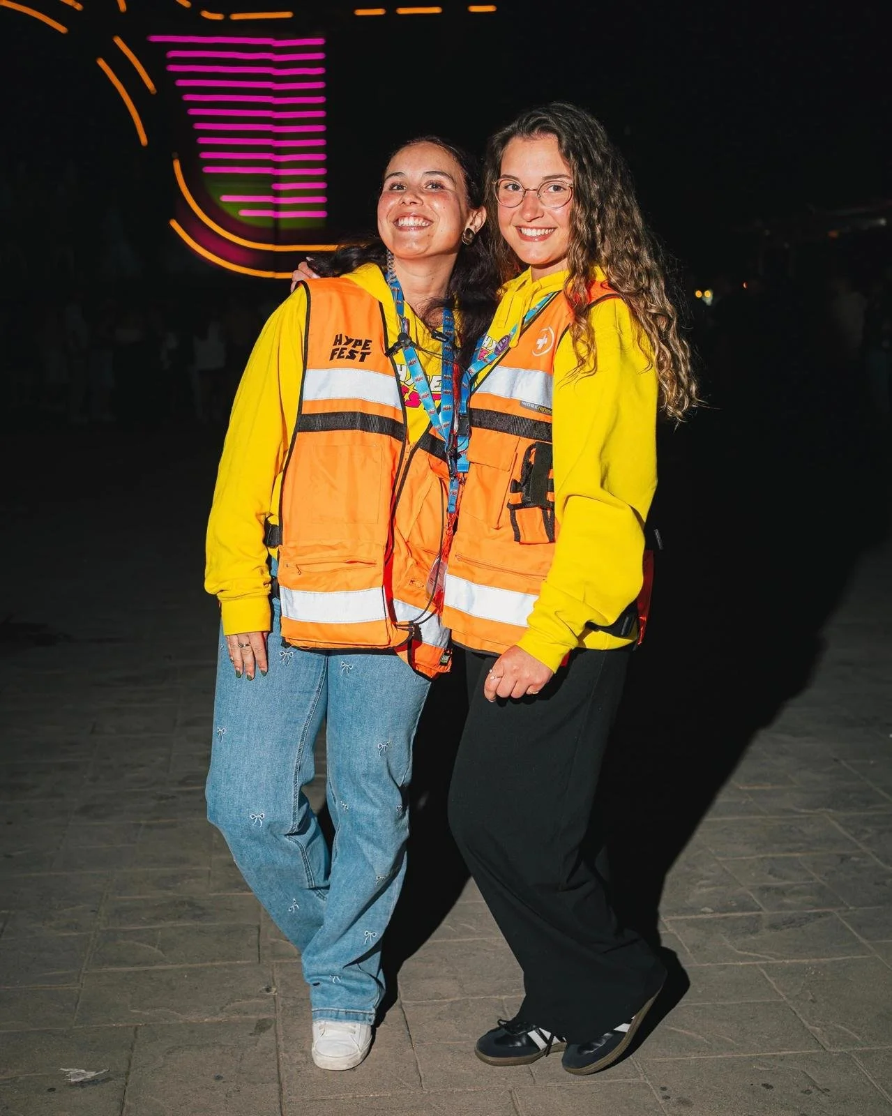 Duas mulheres Signa usando coletes de emergência e roupas amarelas.