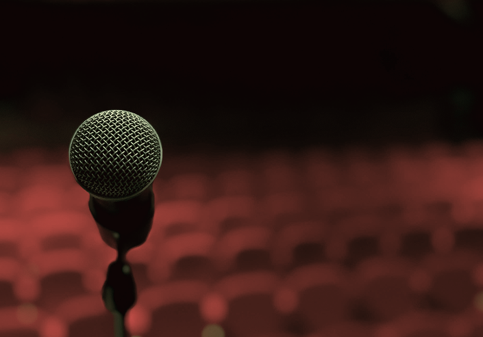 Microphone on a stand in front of an empty auditorium with pink seating