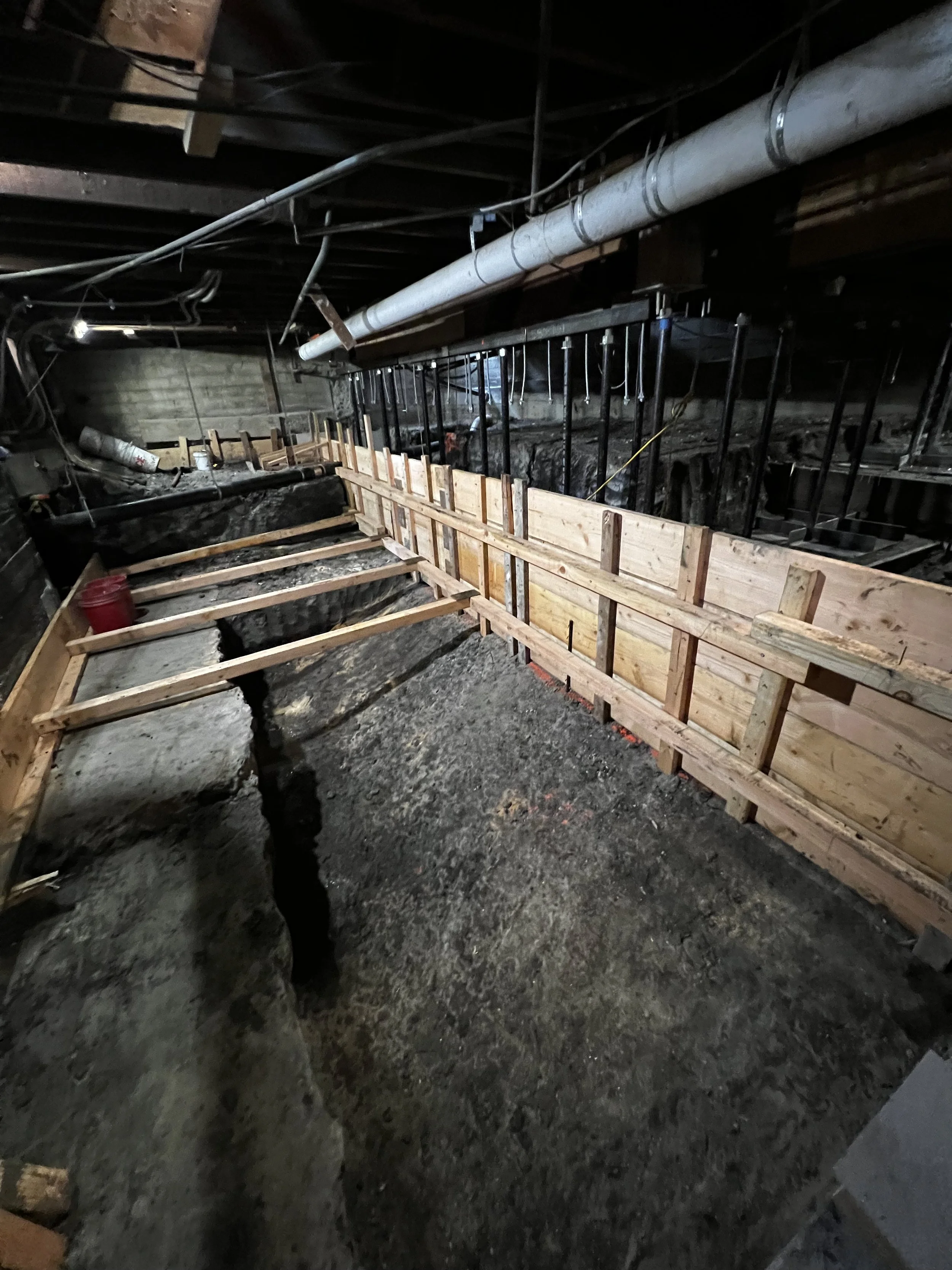 Construction site with wooden framing and bracing in an underground space.