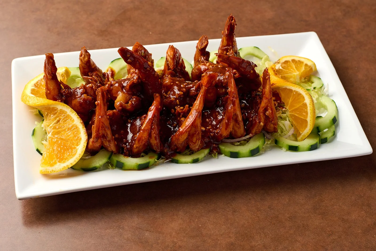 Plate of Asian-style chicken wings with cucumber and orange slices.