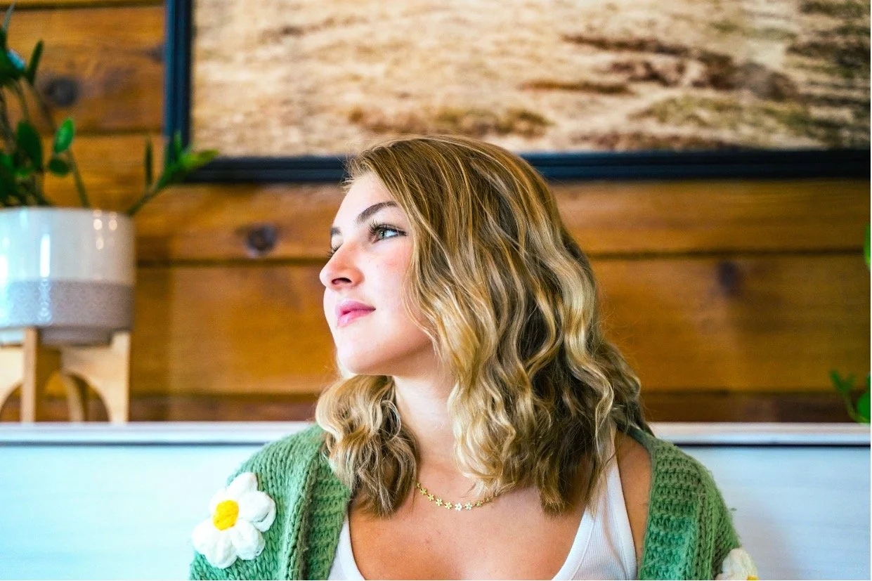 A portrait of Selah Vox looking off into the distance. It includes warm and cool colors, bright to medium lighting. Clear portrait, no grain.