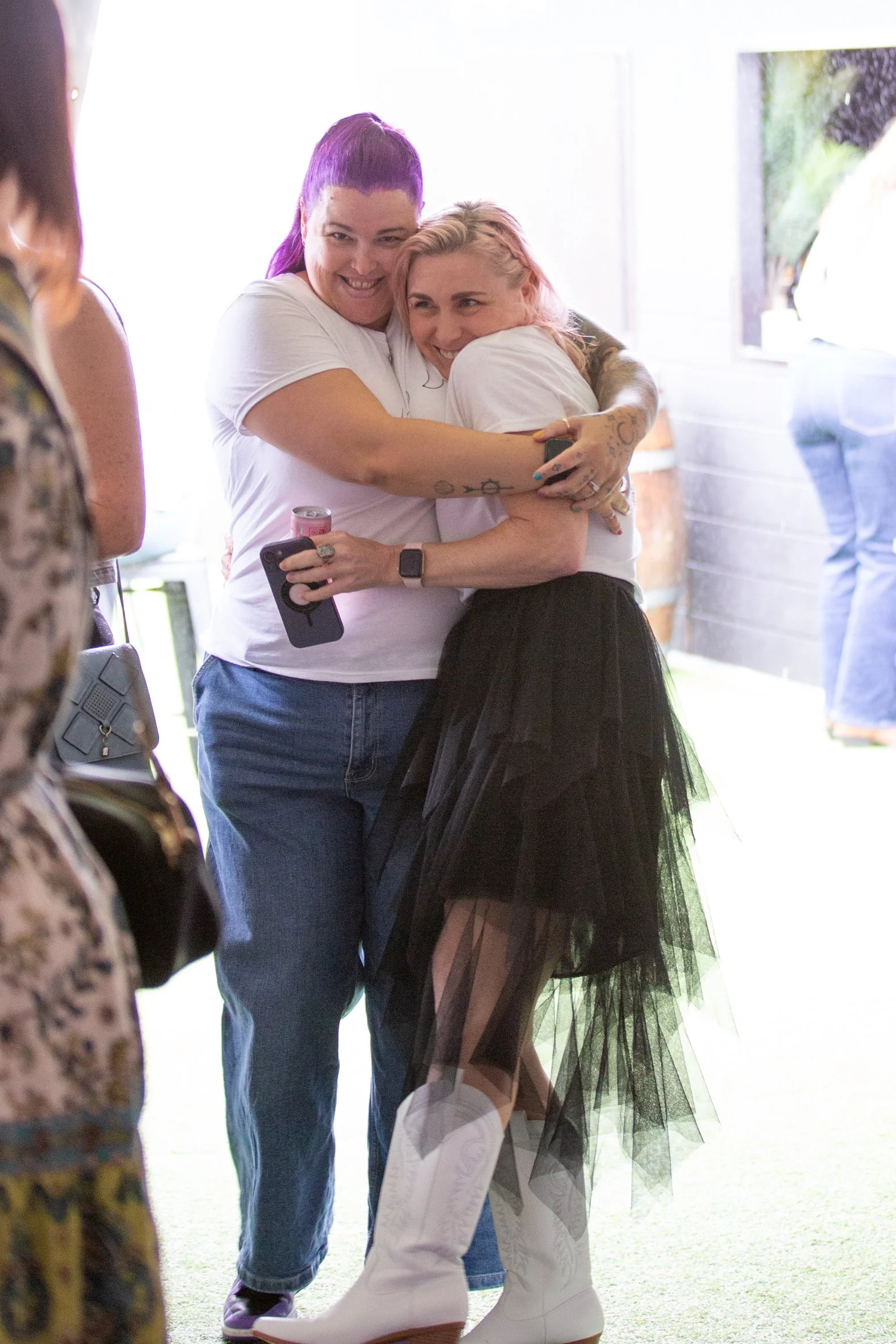 Two women embracing in a friendly hug at the brisbane braless brunch