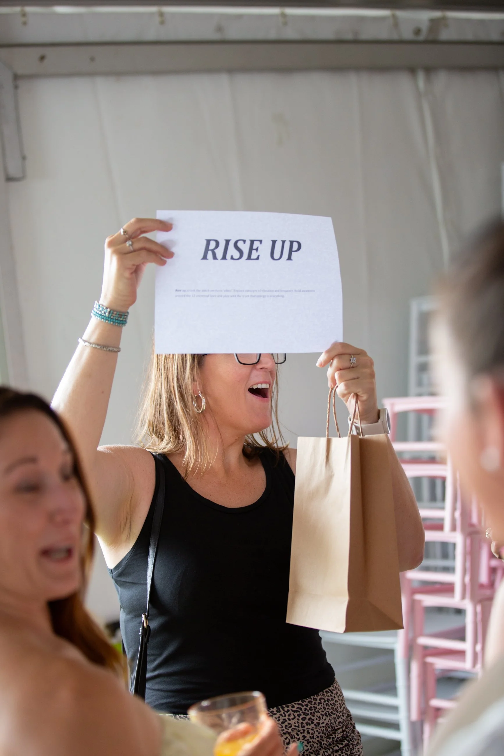 Woman holding a sign that says 'RISE UP' at a Brisbane braless brunch event.