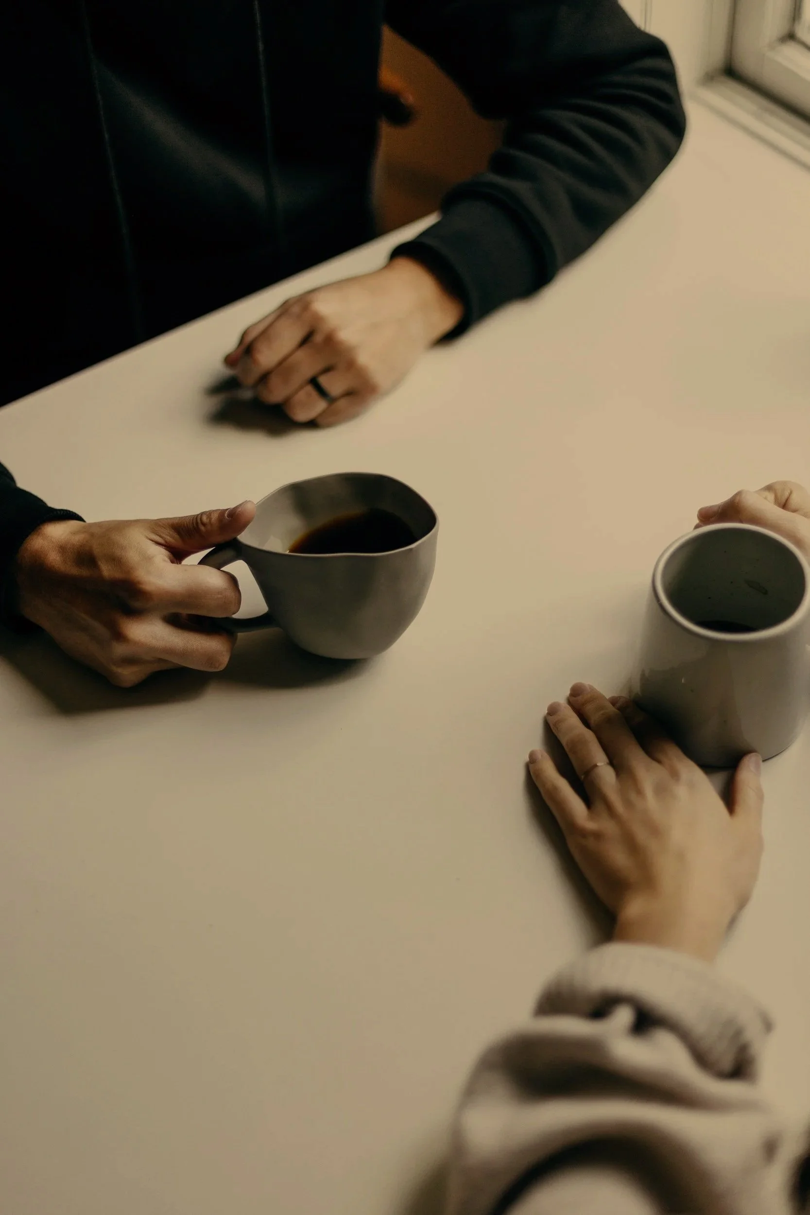 People sitting at a table with coffee cups, engaged in conversation.