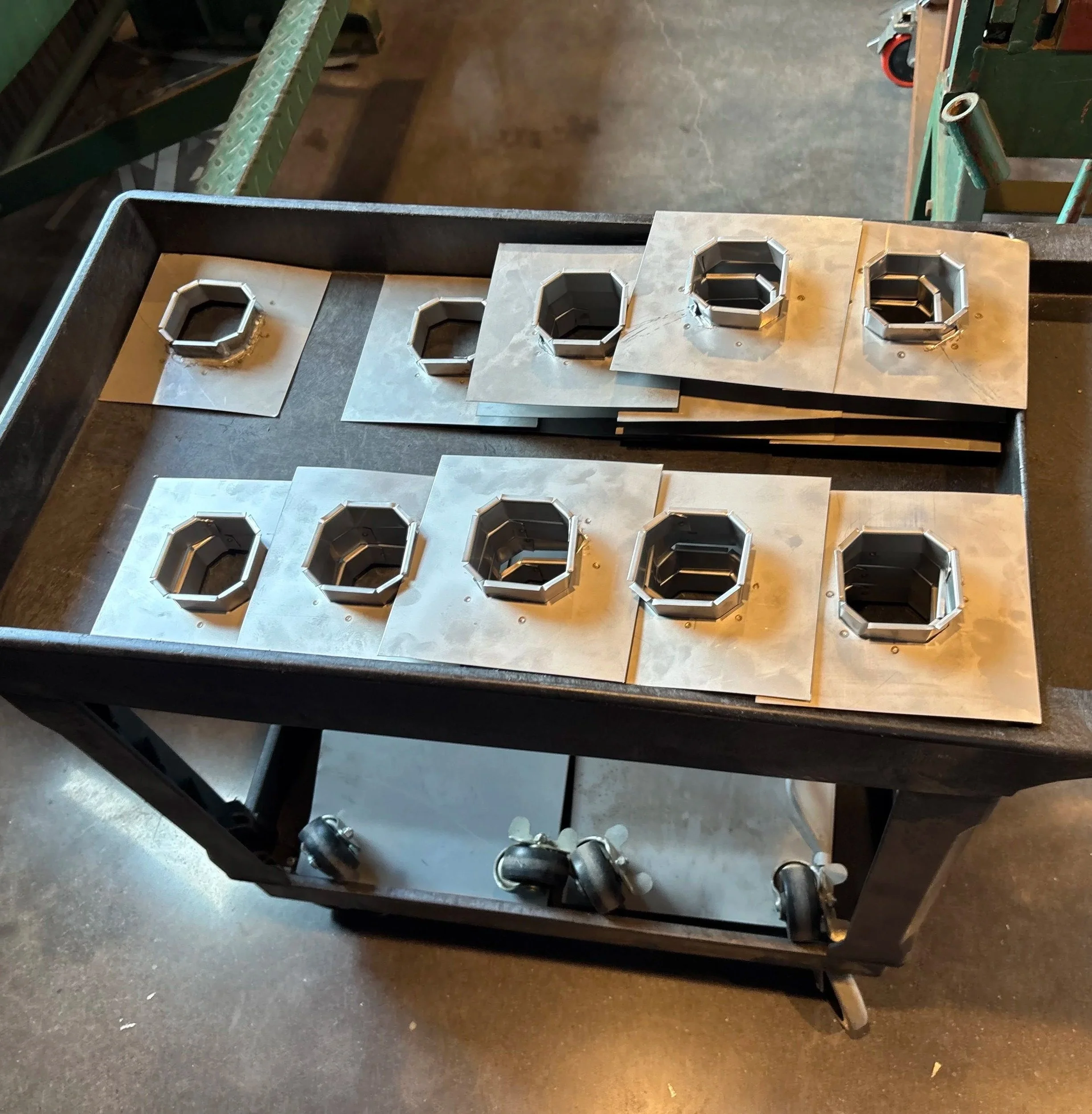 Metal molds with octagonal shapes on a workbench in a workshop.