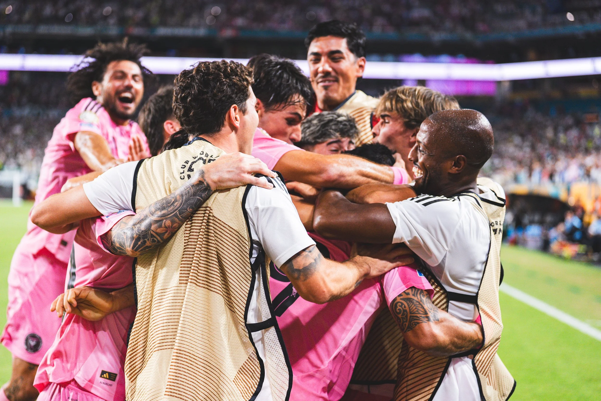 Soccer players in celebration, hugging and cheering on the field in a stadium at night.