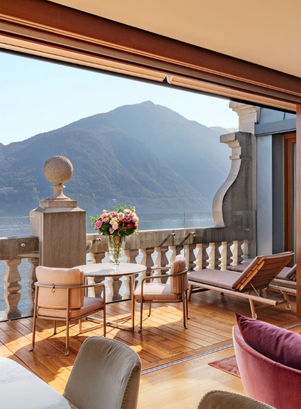 Elegant rooftop suite terrace at Villa Sola Cabiati on Lake Como with mountain views, plush lounge chairs and fresh flowers, exemplifying the exclusive villa stays arranged by Carte Blanche Advisors