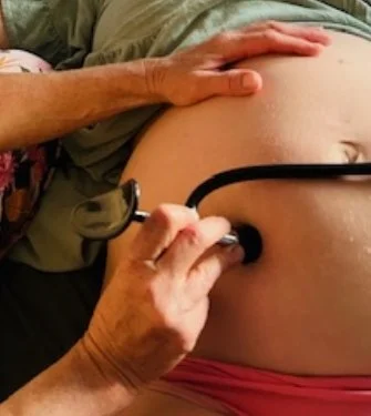A person holding an ultrasound probe against a pregnant woman's abdomen.