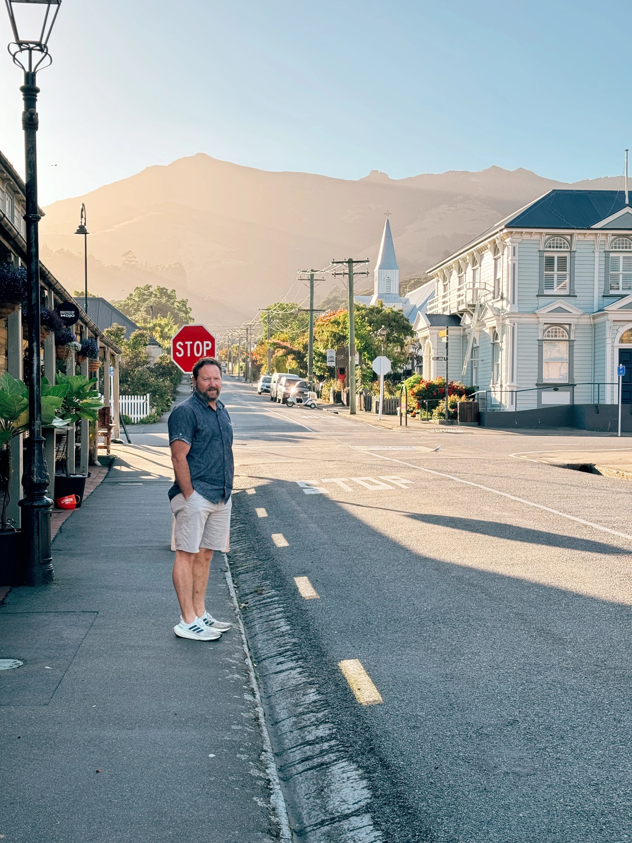 T Dunn in Akaroa Village with pretty morning light across the hills and historical buildings