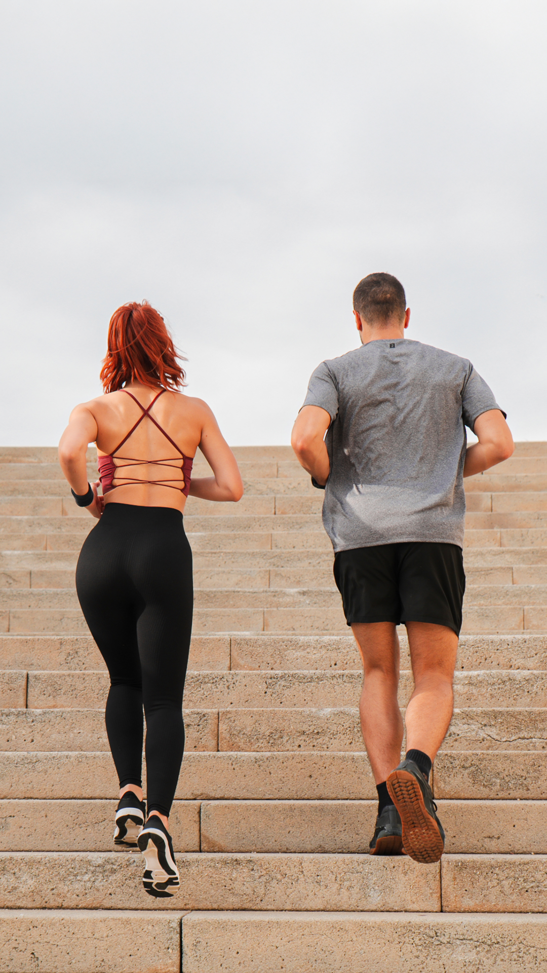 Man and Woman running up steps in athletic gear