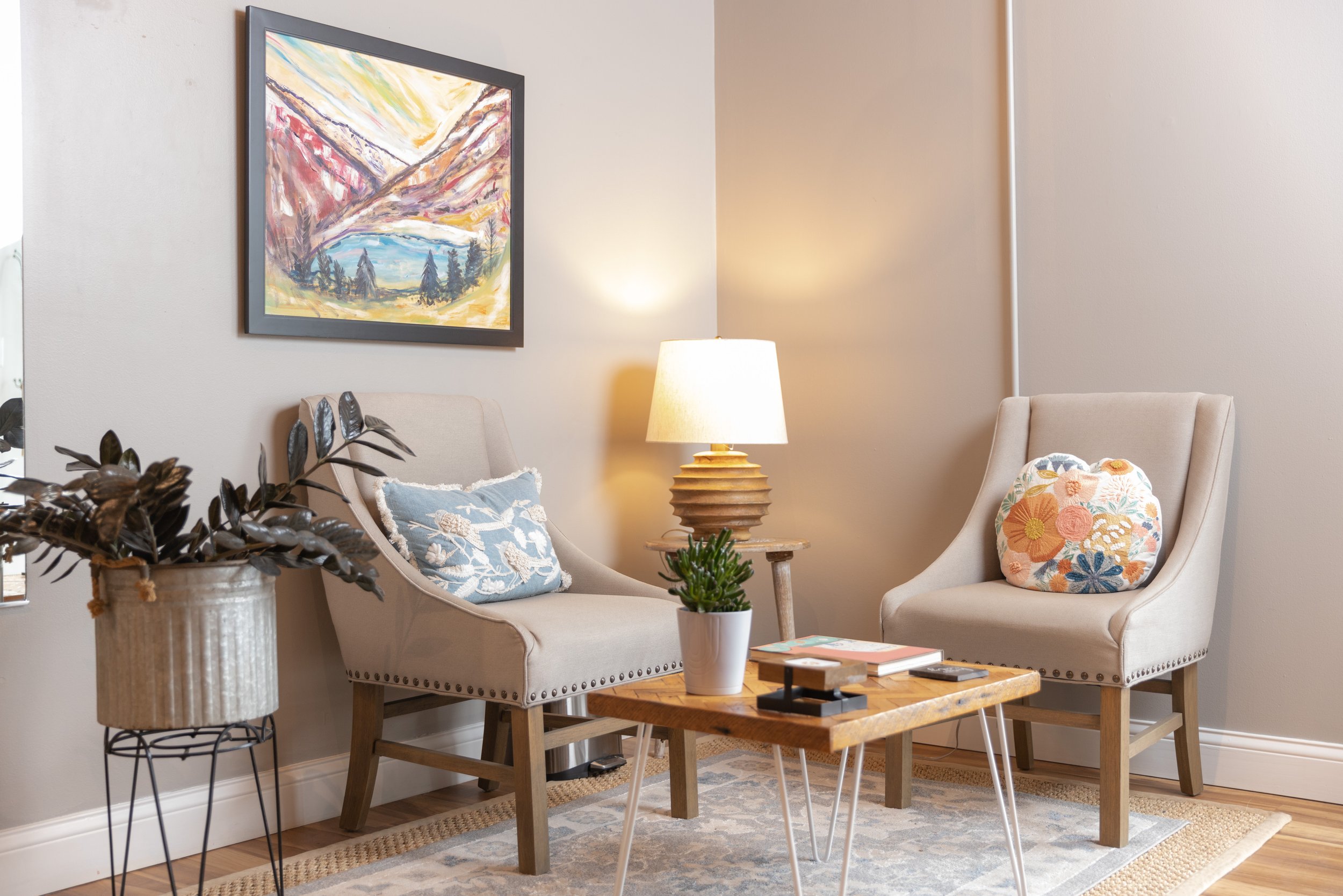 Waiting area with two chairs, lamp, wall art, and coffee table