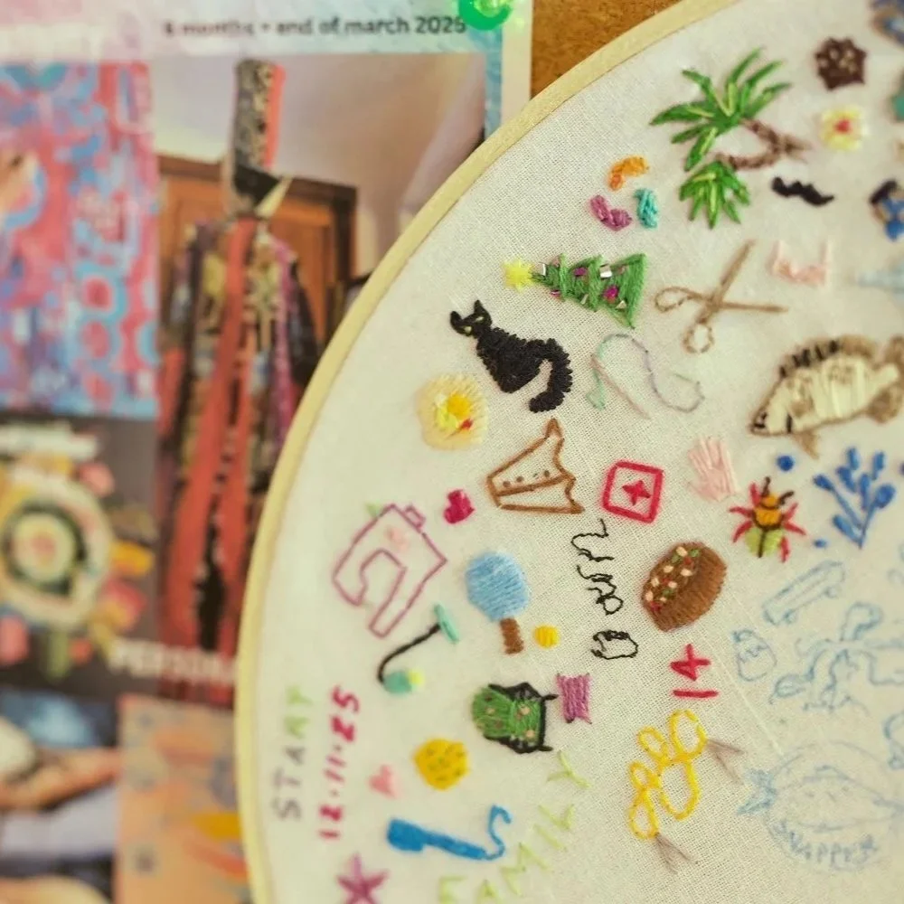 Embroidery hoop showing visible mending samples and decorative stitching for clothing repair.