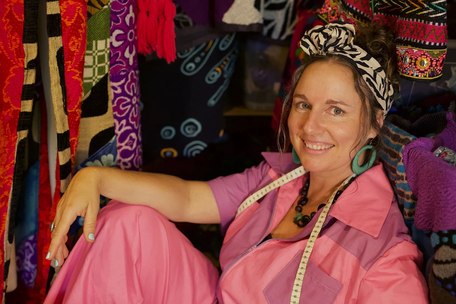 Corinne Wilson surrounded by colourful textiles, reflecting her journey into upcycled clothing and sewing.