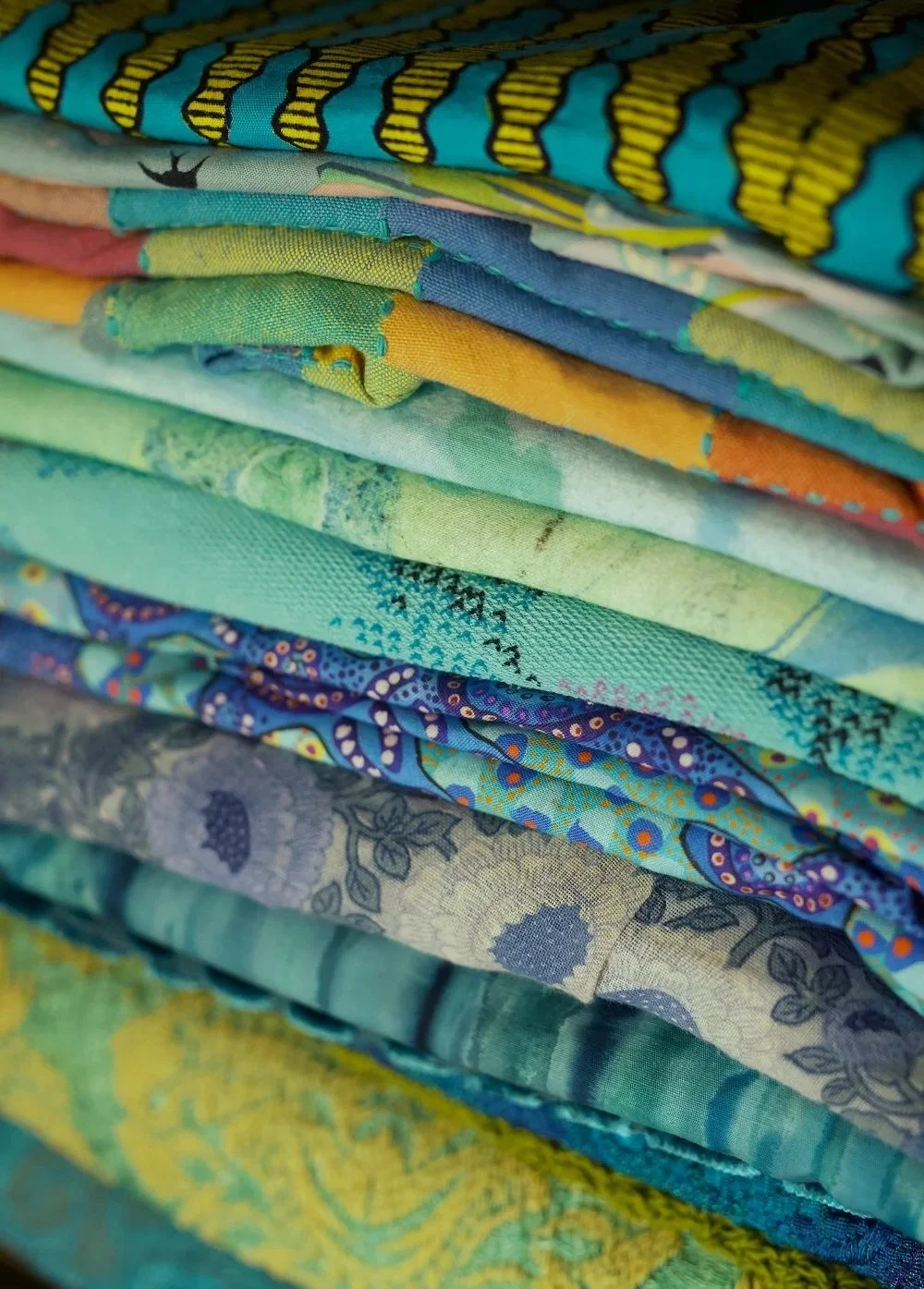 Stack of colourful fabrics used for clothing alterations, textile mending and creative repairs.