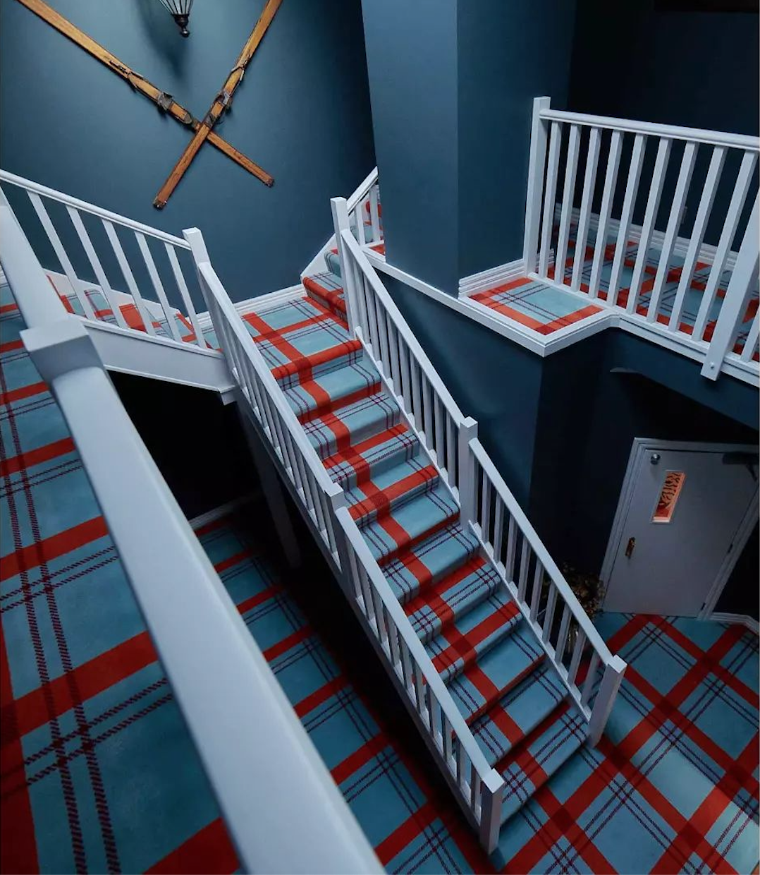Hospitality staircase with red and blue plaid carpet and vintage ski wall display