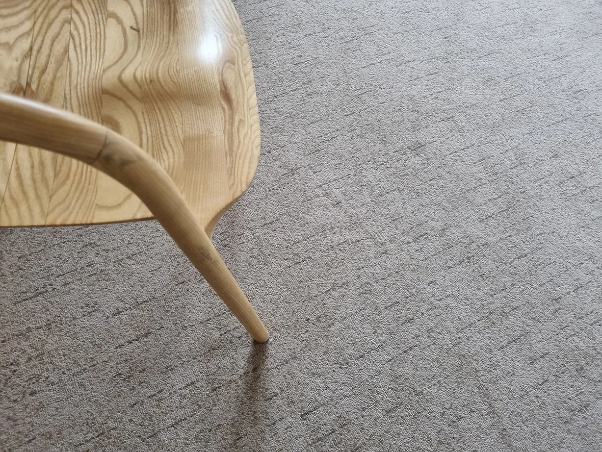 lose-up of curved wooden chair leg on gray Axminster carpet
