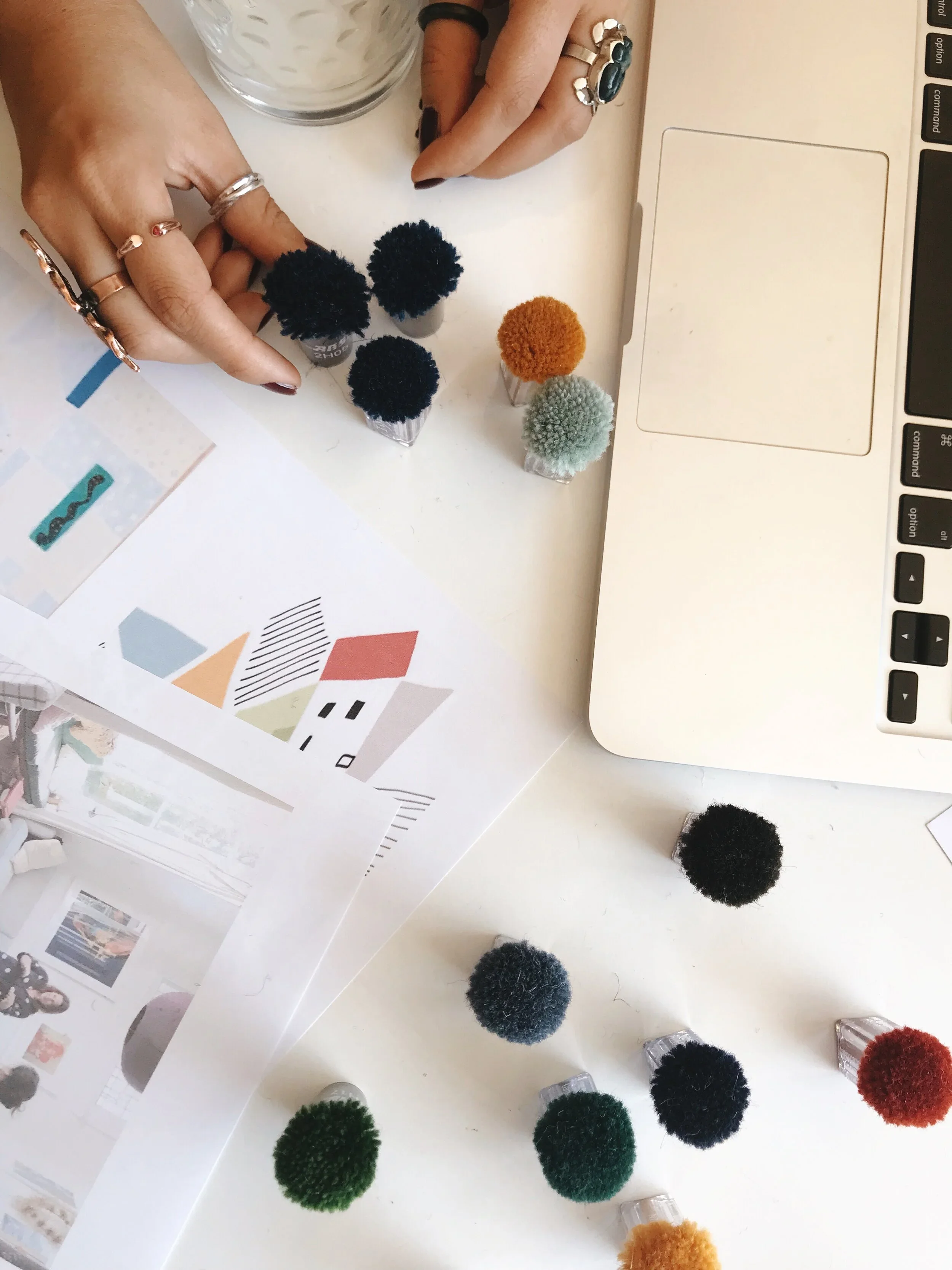 Design studio table with colorful pom-pom carpet samples and swatch sheets