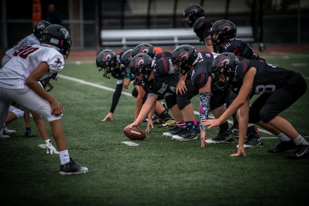 Football game showing two teams in a crouched offensive and defensive line at the line of scrimmage.