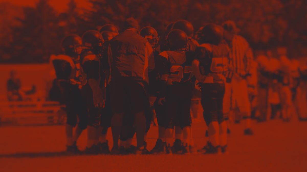 Football coach talking to young players in huddle