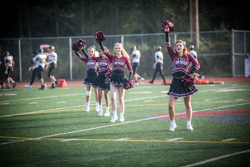 Cheerleaders performing during a football game on a turf field