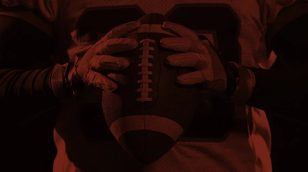 Football player holding a football with both hands.