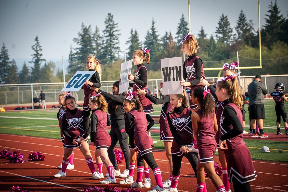 Cheerleaders on a football field holding signs during a game.