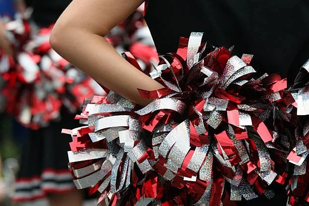 Cheerleader holding red, silver, and black pom-poms
