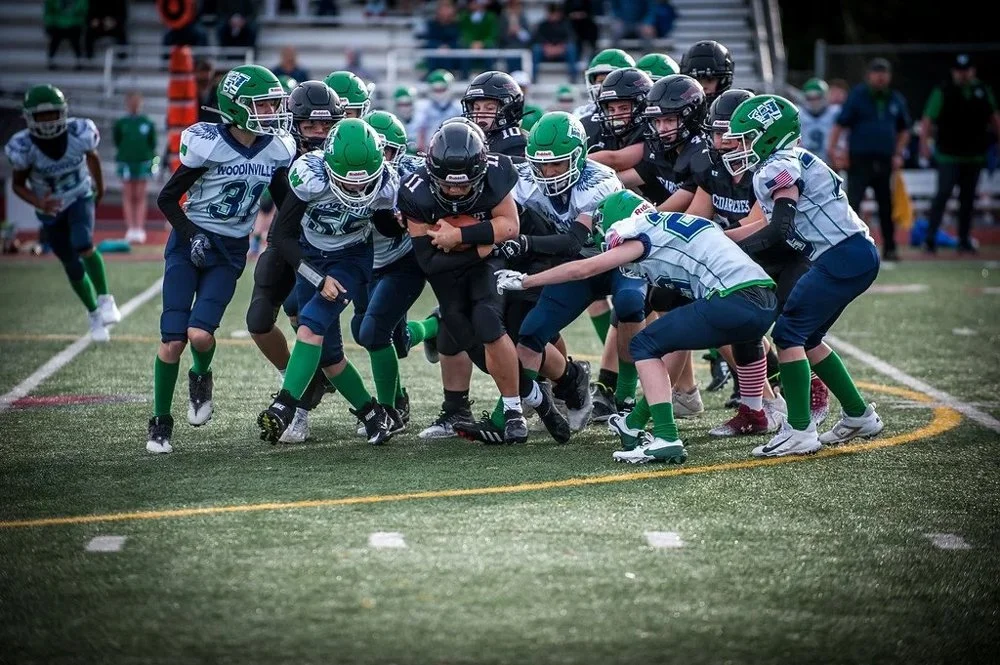 Youth football players are engaged in a push during a game.