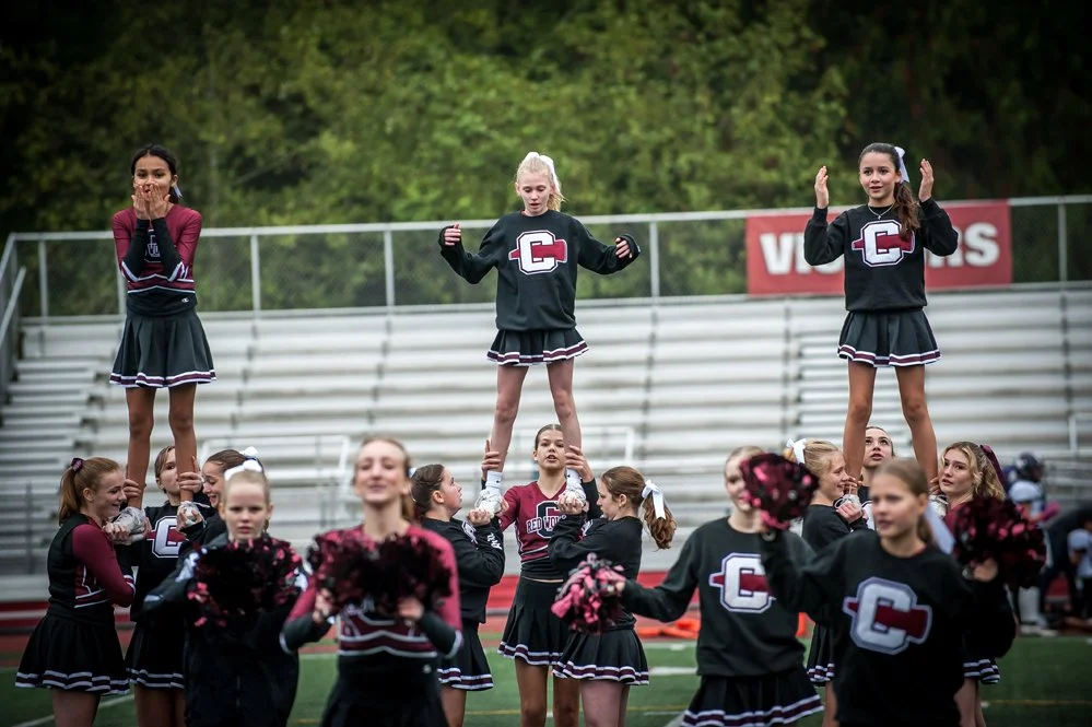 Cheerleaders performing a stunt on a football field during a game.